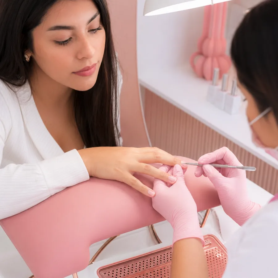 Manicure profesional con acabado rosado en estudio de belleza.